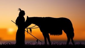 A Native American with a horse at sunset